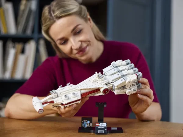 Adult placing Lego Star Wars Tantive IV on display stand